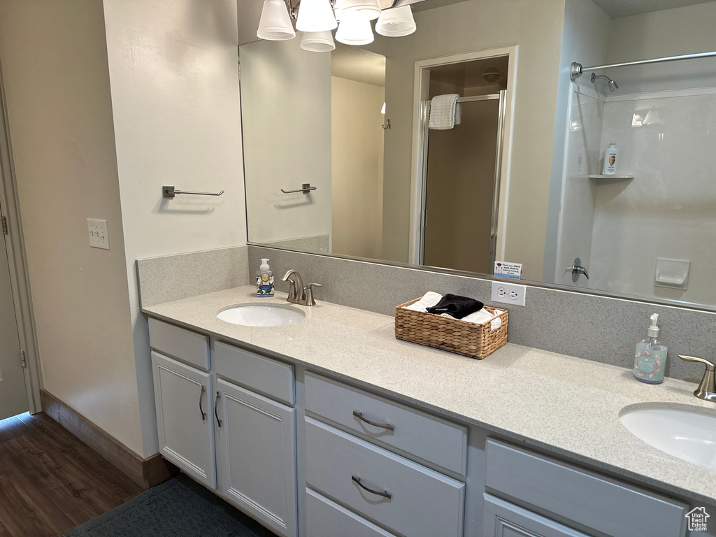 Bathroom with a shower with shower door, wood finished floors, and vanity
