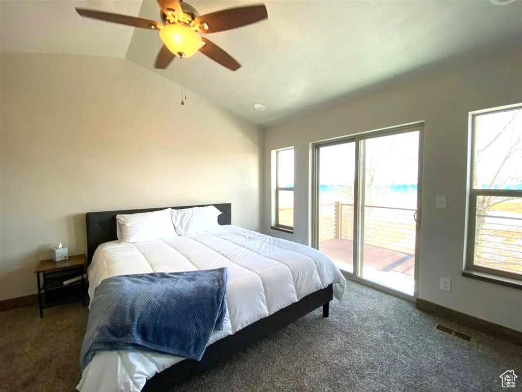 Bedroom featuring access to outside, vaulted ceiling, carpet flooring, and multiple windows
