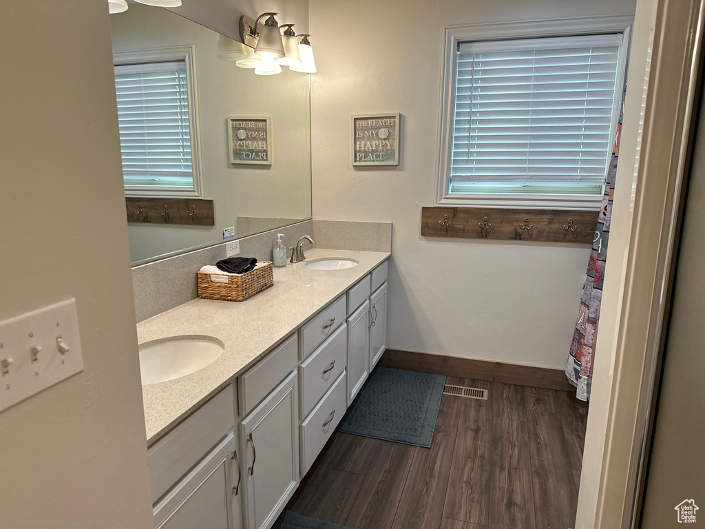Bathroom featuring double vanity, wood finished floors, and baseboards