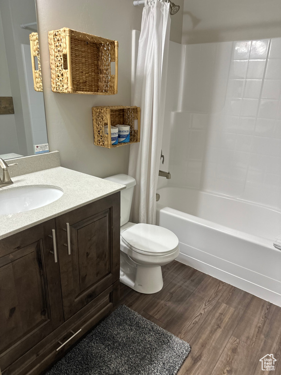 Bathroom with wood finished floors, toilet, shower / tub combo with curtain, and vanity