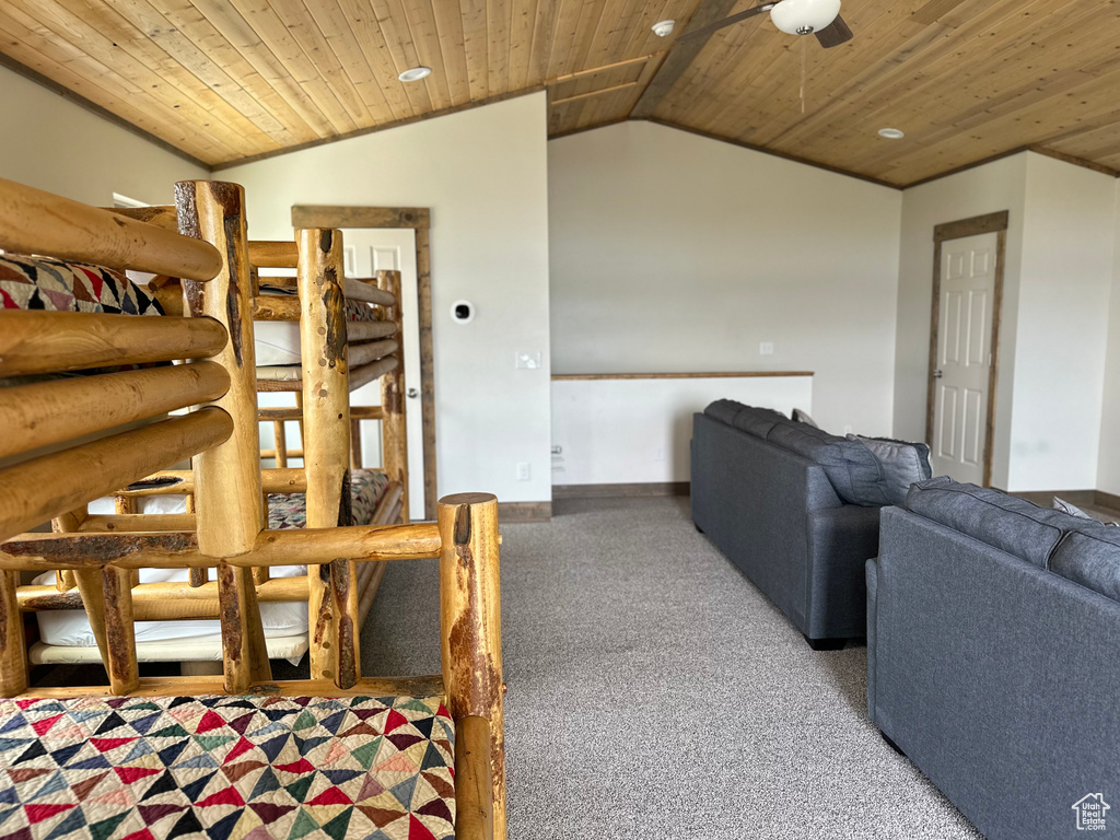 Living area featuring vaulted ceiling, wood ceiling, carpet flooring, ceiling fan, and baseboards