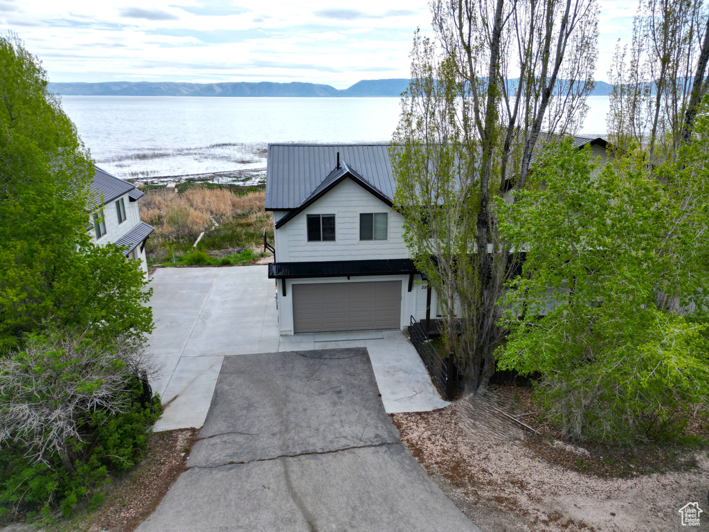 View of front facade with asphalt driveway, a garage, a water and mountain view, and metal roof