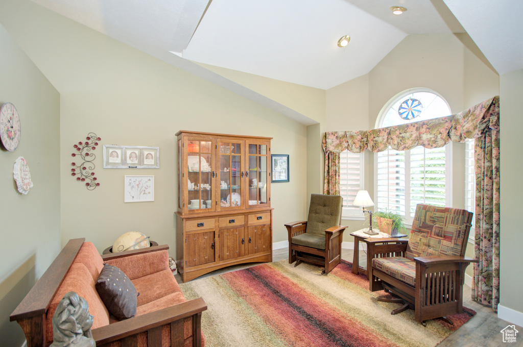 Living area featuring high vaulted ceiling, wood finished floors, and baseboards
