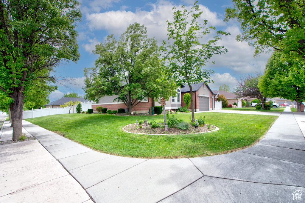 View of property hidden behind natural elements with driveway, an attached garage, and a residential view
