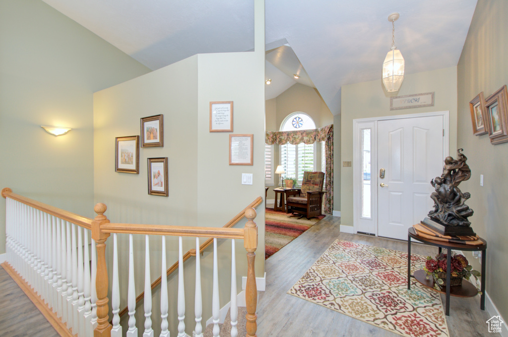 Entryway with vaulted ceiling, wood finished floors, and baseboards