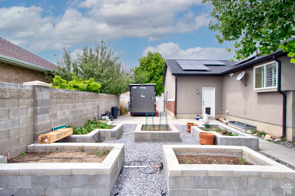 View of patio with a garden, a fenced backyard, a shed, and an outdoor structure