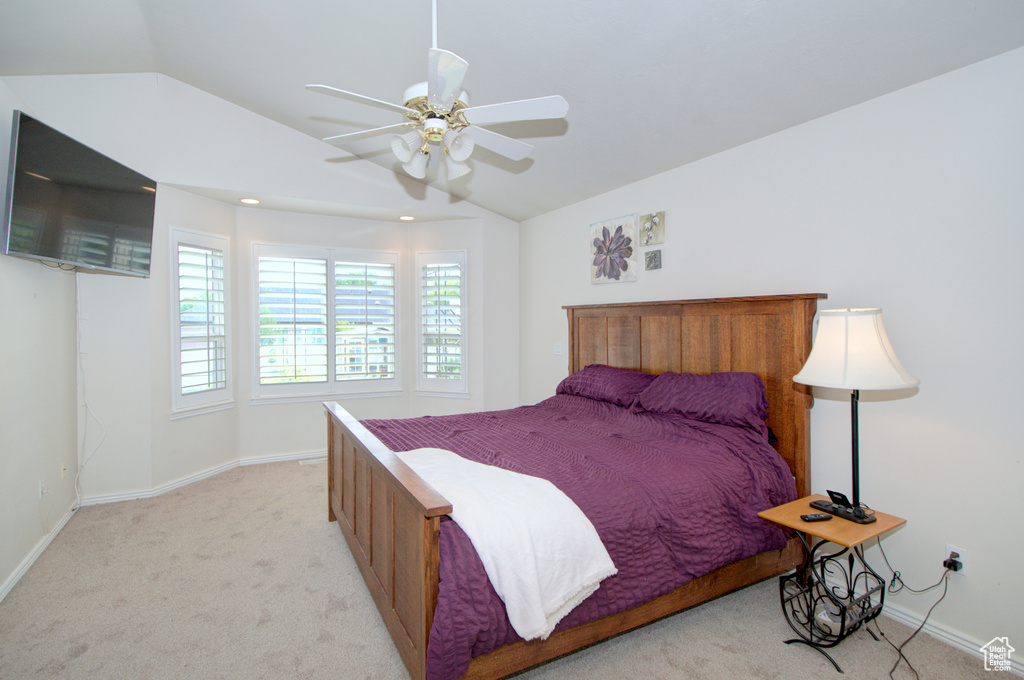 Bedroom with vaulted ceiling, light carpet, baseboards, and ceiling fan