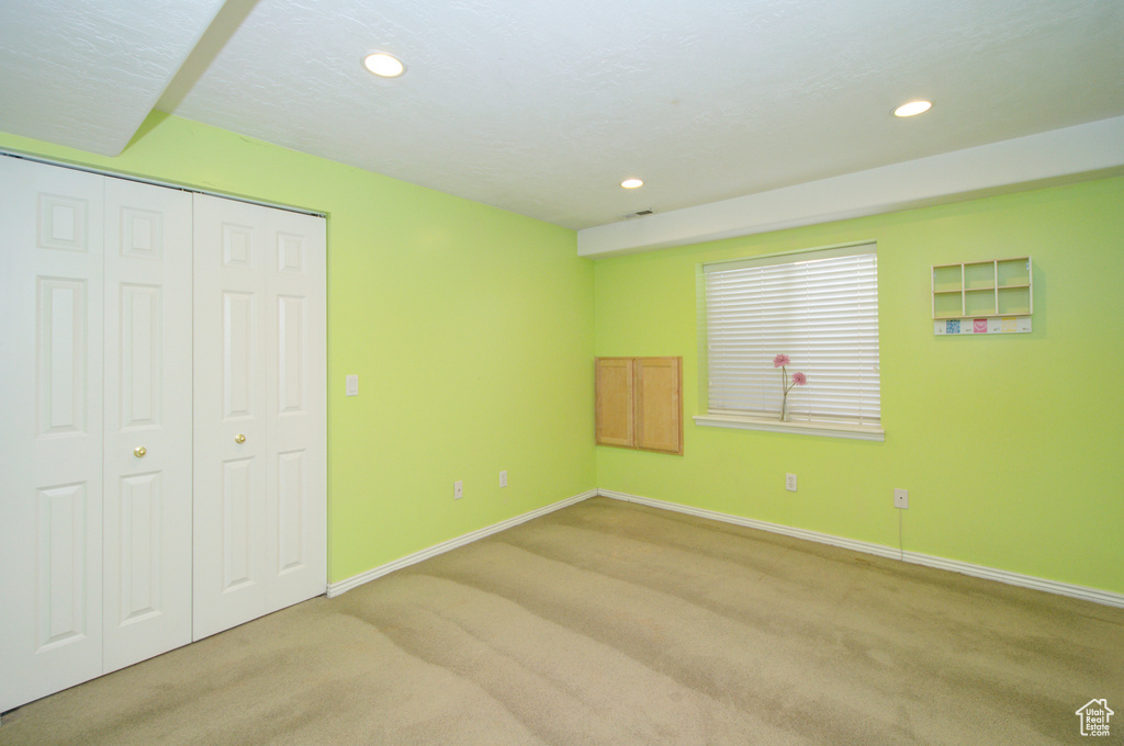 Unfurnished bedroom featuring light carpet, baseboards, recessed lighting, and a closet