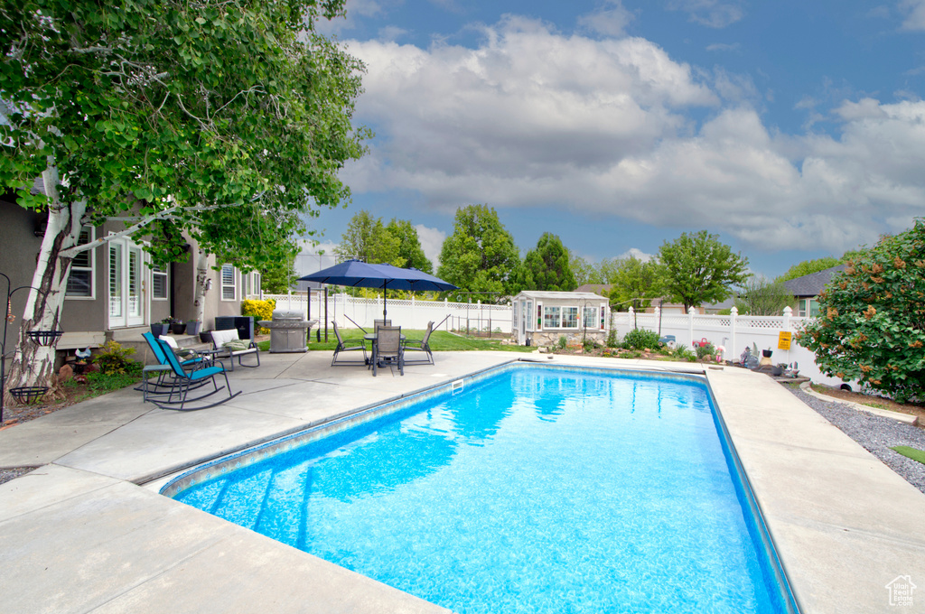 View of pool featuring a patio, a fenced backyard, an outbuilding, and french doors