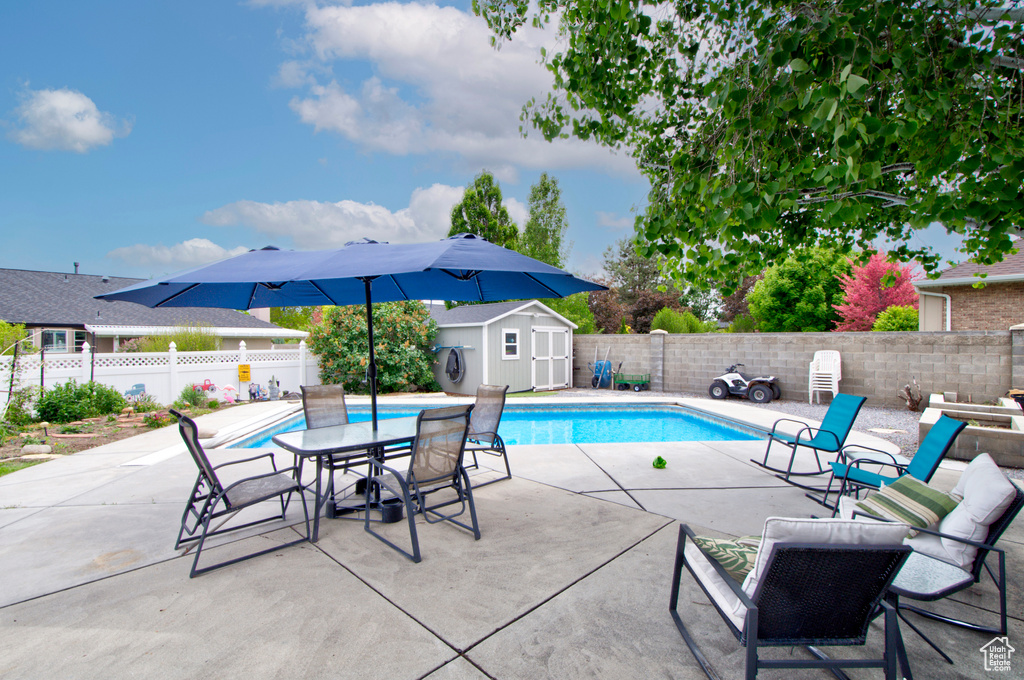 View of pool featuring a storage unit, an outdoor structure, a patio, and a fenced backyard
