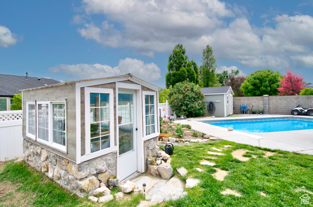 View of pool featuring an outdoor structure, a fenced backyard, and a shed
