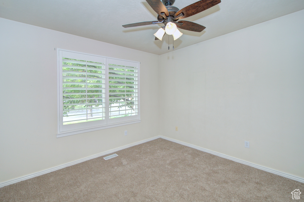 Carpeted empty room featuring baseboards and a ceiling fan