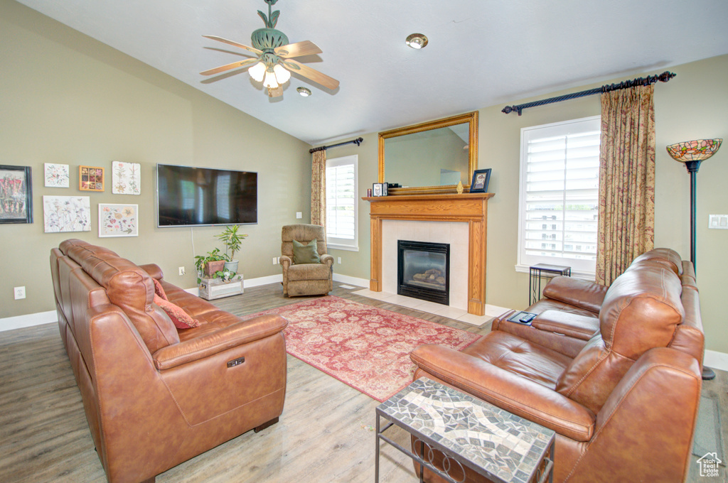 Living area with ceiling fan, wood finished floors, vaulted ceiling, a fireplace with flush hearth, and baseboards