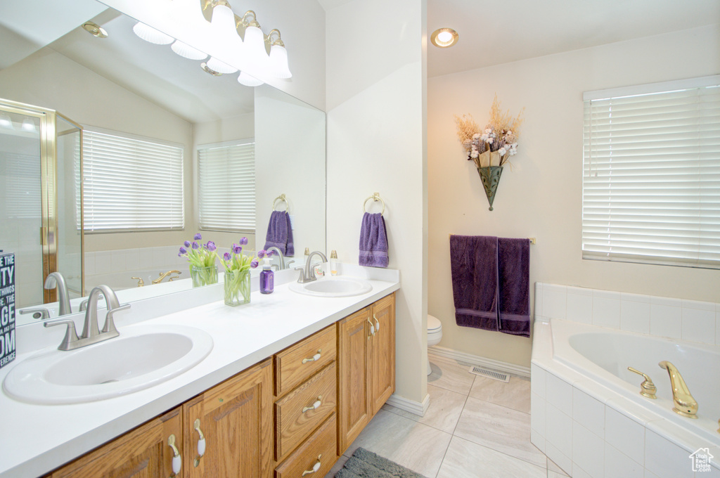 Bathroom with double vanity, toilet, a bath, a shower with shower door, and tile patterned flooring
