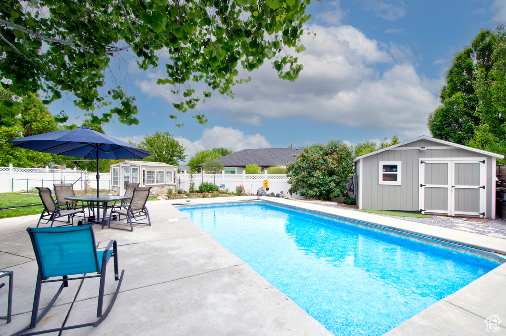 View of pool featuring an outbuilding, a fenced backyard, and a patio