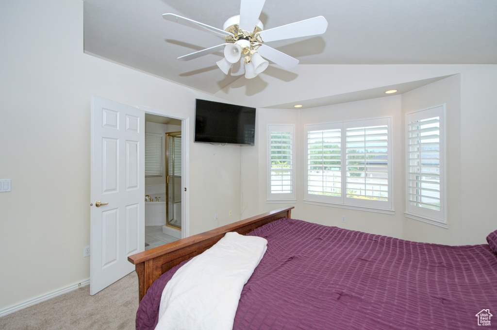 Bedroom with light colored carpet, multiple windows, vaulted ceiling, a ceiling fan, and ensuite bath