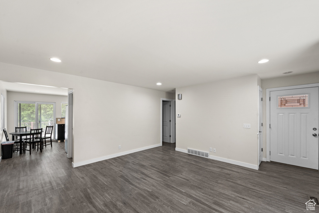 Unfurnished living room featuring dark wood-style floors, recessed lighting, and baseboards