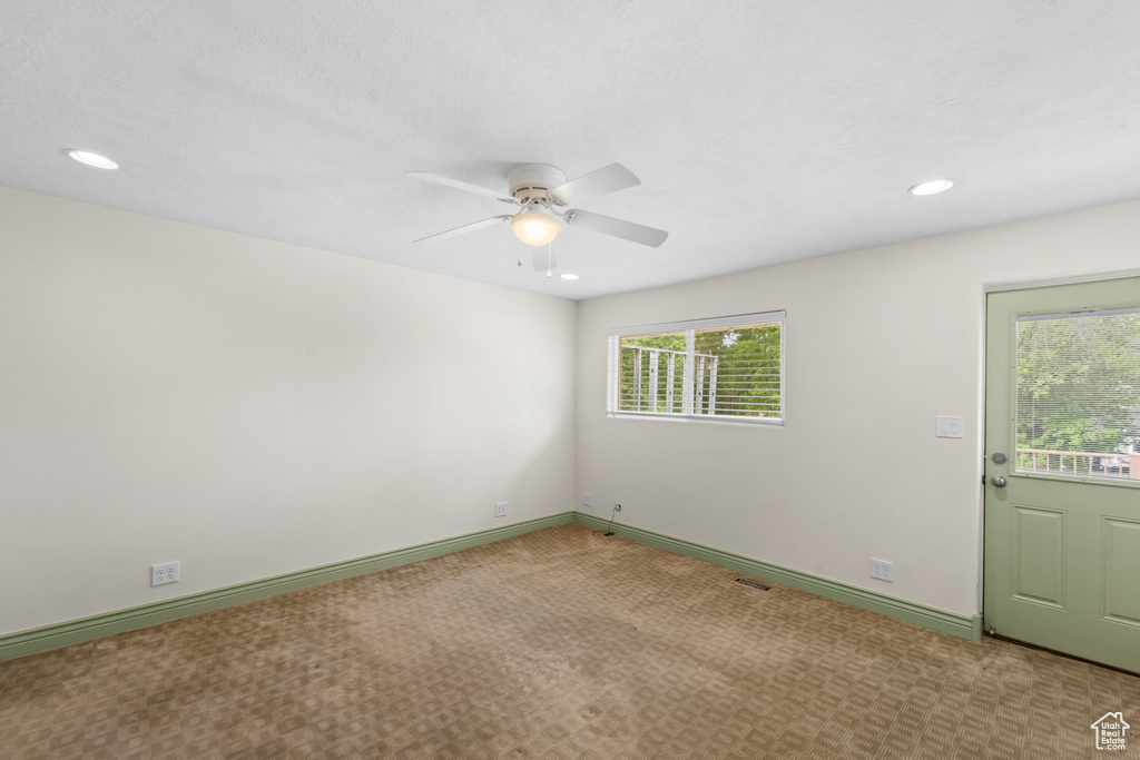 Carpeted empty room featuring healthy amount of natural light, a ceiling fan, recessed lighting, and baseboards