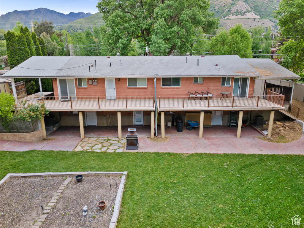 Rear view of house with a patio, a yard, and a deck with mountain view