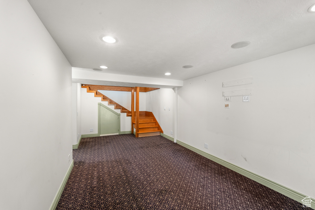 Finished below grade area featuring stairway, dark carpet, recessed lighting, and baseboards