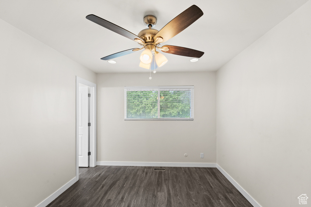 Spare room featuring dark wood-type flooring, baseboards, and a ceiling fan