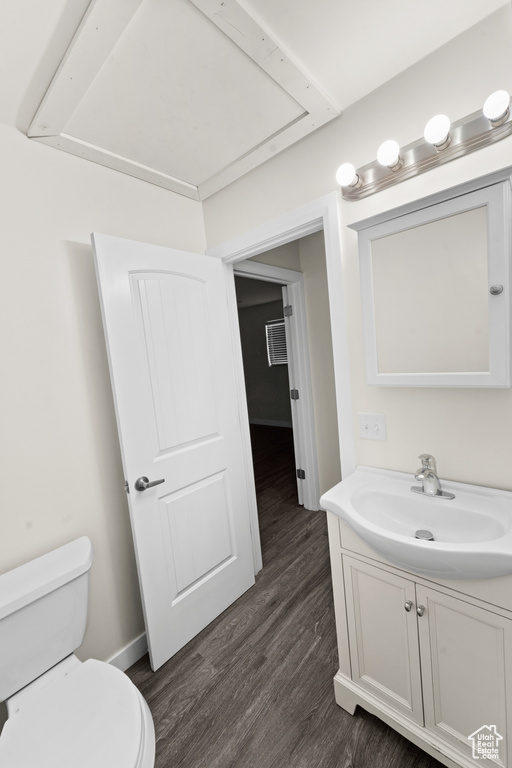 Bathroom with toilet, vanity, wood finished floors, and baseboards