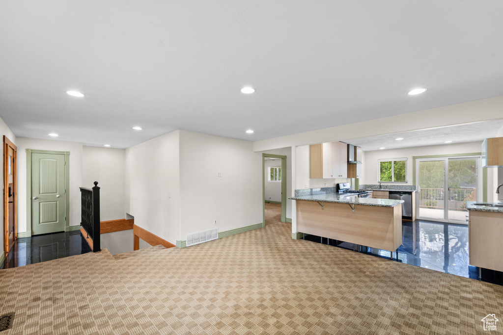 Kitchen with stove, light stone countertops, recessed lighting, baseboards, and dishwasher