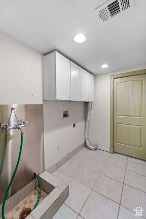 Washroom featuring electric dryer hookup, hookup for a washing machine, cabinet space, light tile patterned floors, and recessed lighting