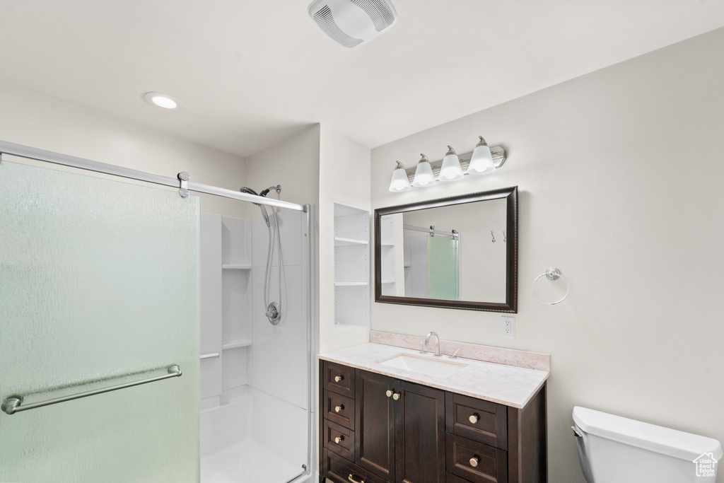 Bathroom featuring a stall shower, toilet, and vanity
