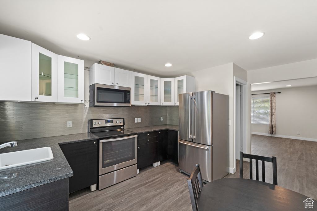Kitchen featuring appliances with stainless steel finishes, a sink, light wood-style flooring, white cabinetry, and recessed lighting