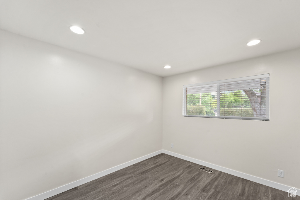 Spare room with dark wood-style floors, baseboards, and recessed lighting