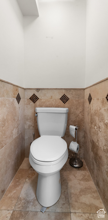 Bathroom with toilet, tile walls, and a wainscoted wall