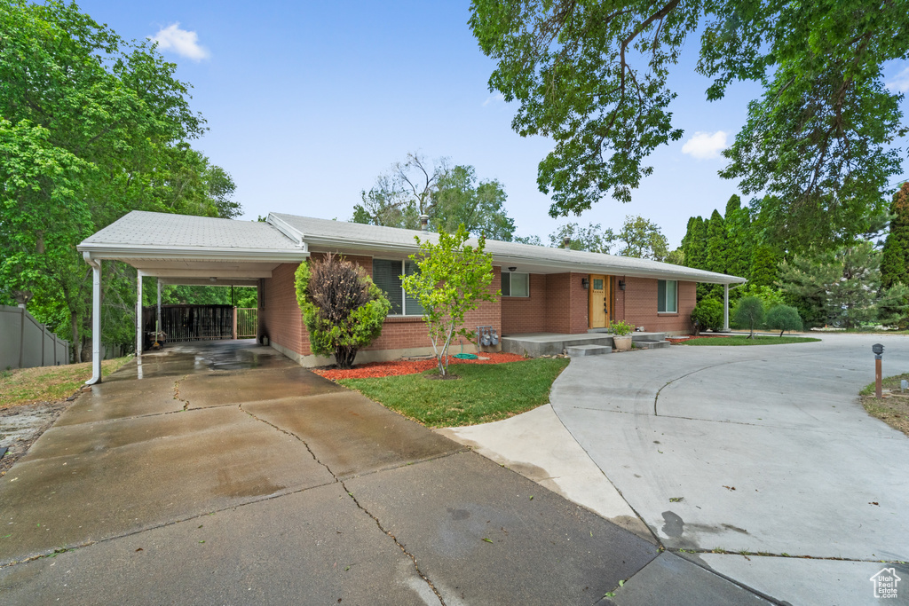 Single story home with concrete driveway, an attached carport, and brick siding