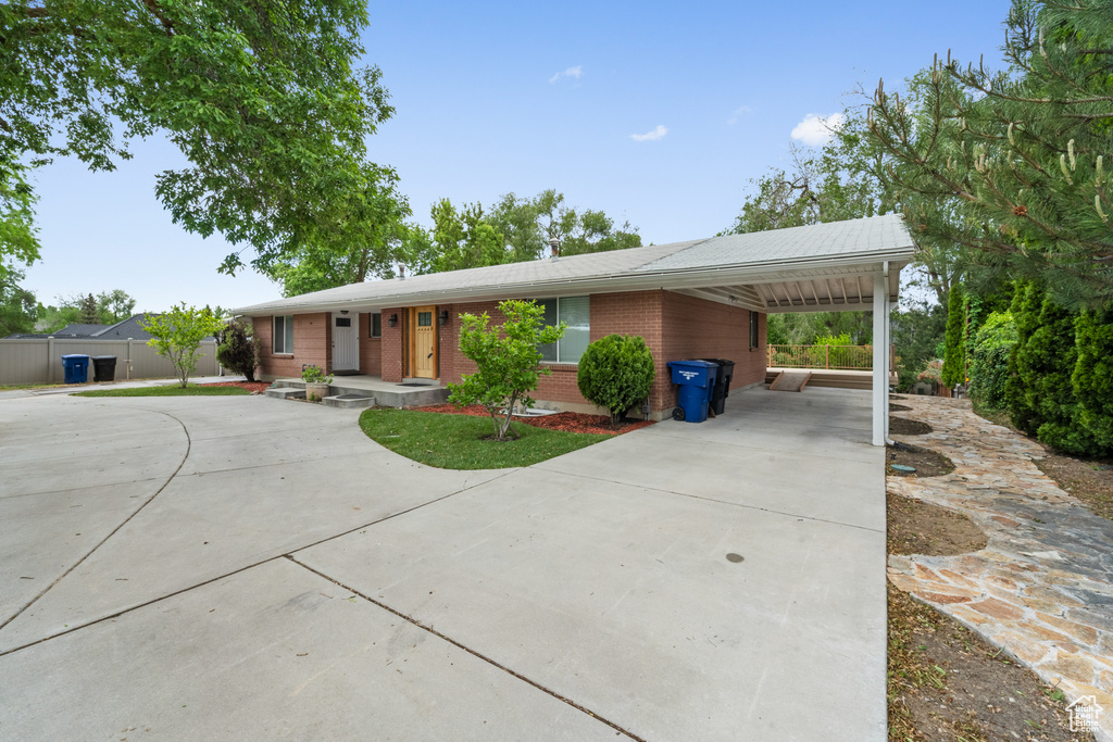 Ranch-style house with concrete driveway, brick siding, an attached carport, and fence