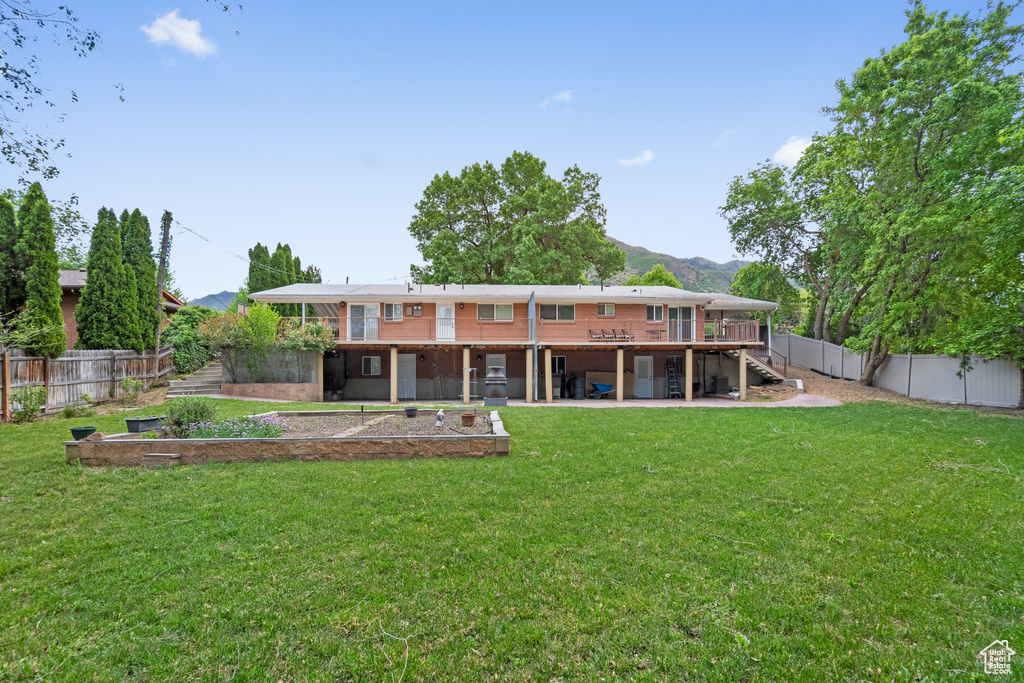 Back of house with stairway, a deck with mountain view, and a patio area