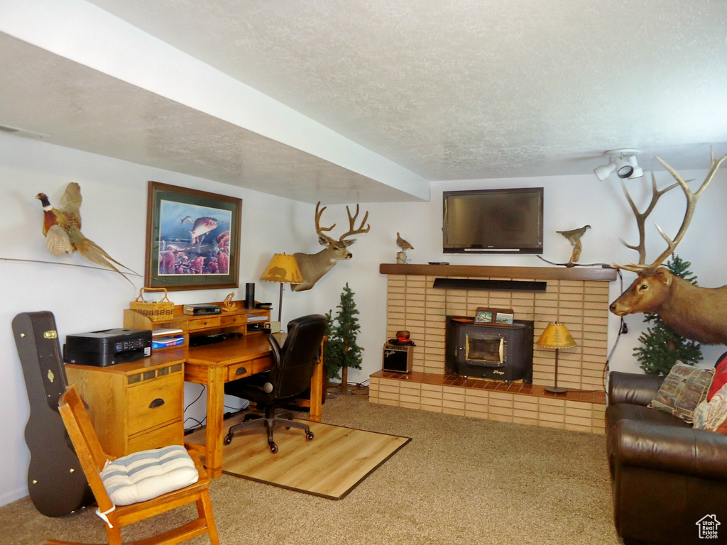 Carpeted home office with a textured ceiling and a wood stove