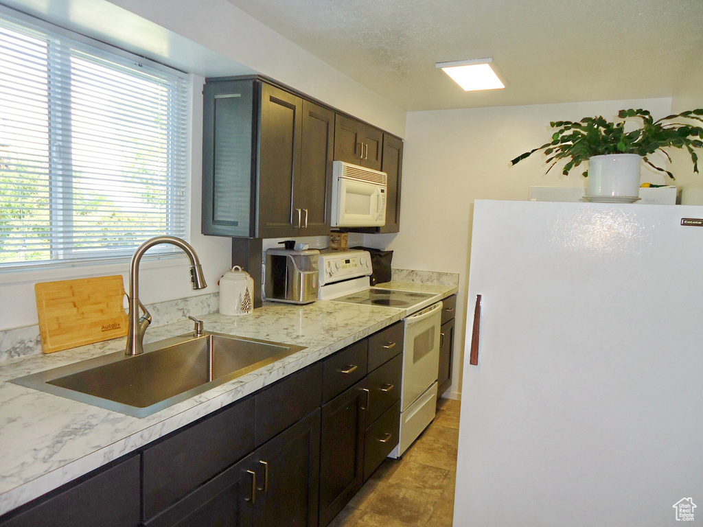 Kitchen with white appliances, a sink, and dark brown cabinets