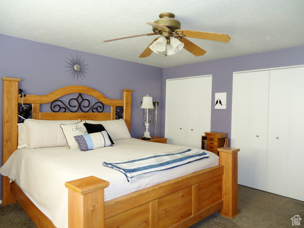 Bedroom with two closets, carpet, and ceiling fan