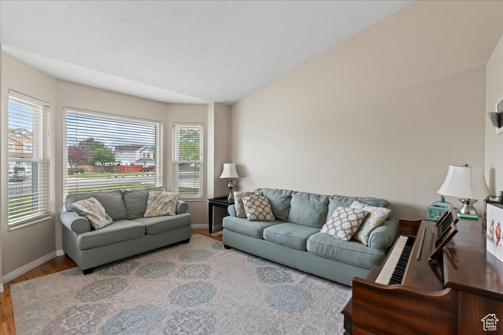 Living area with baseboards, wood finished floors, and lofted ceiling