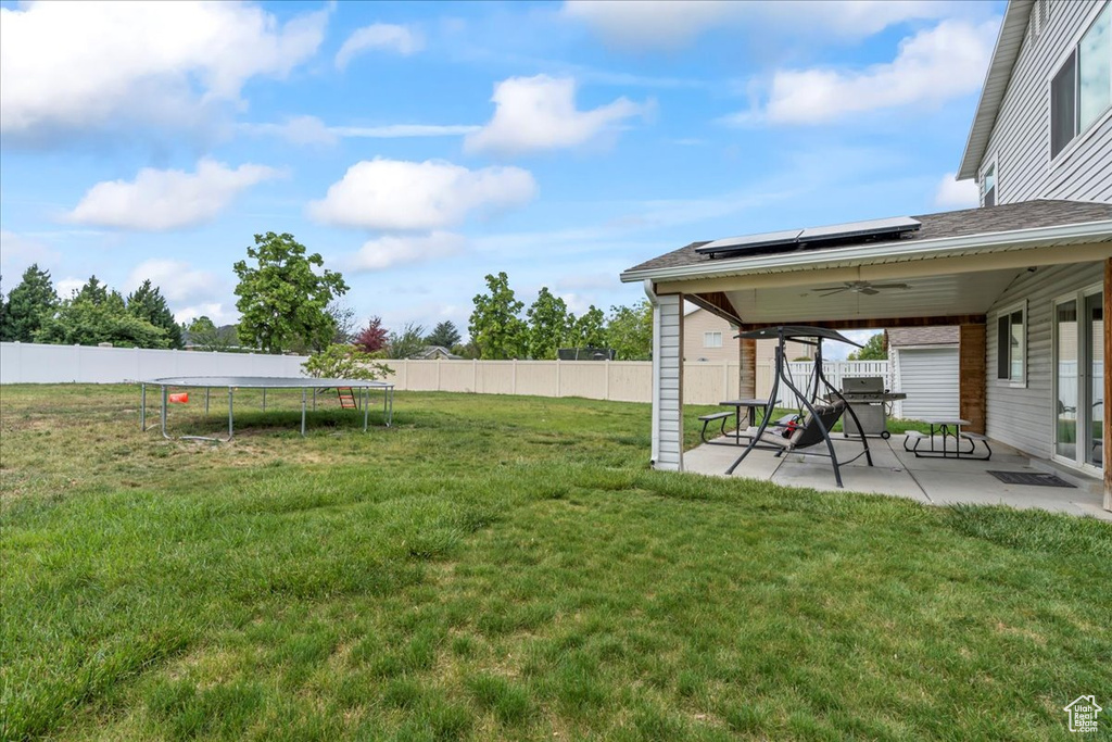 View of yard featuring a trampoline, a patio, and ceiling fan