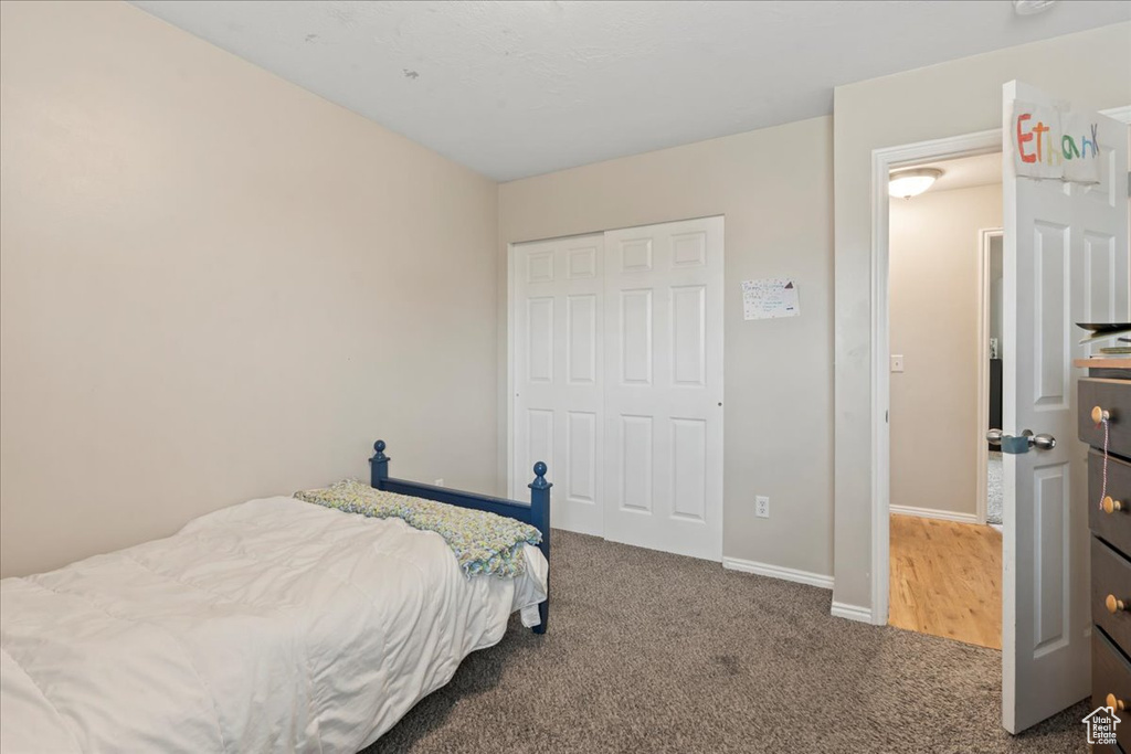 Carpeted bedroom featuring a closet and baseboards