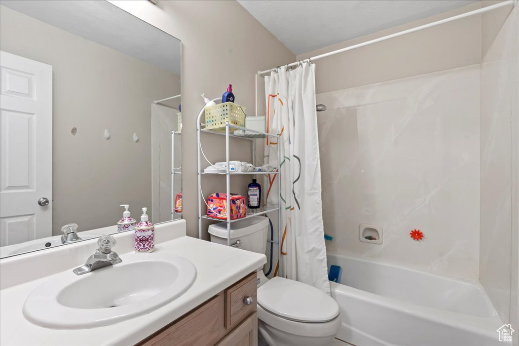 Bathroom with toilet, shower / bath combo with shower curtain, and vanity