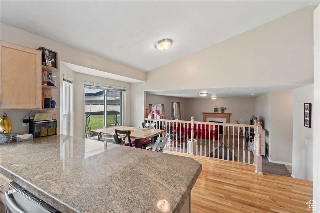 Kitchen featuring light brown cabinets, light wood-style floors, a peninsula, open shelves, and vaulted ceiling