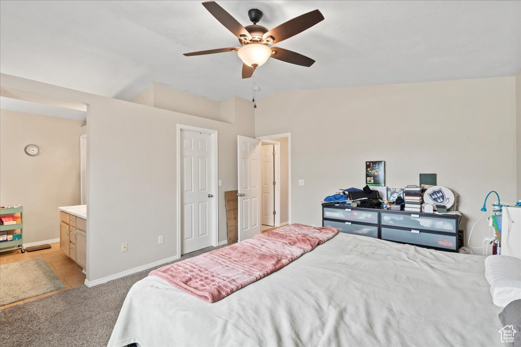 Bedroom featuring light carpet, baseboards, ceiling fan, connected bathroom, and lofted ceiling