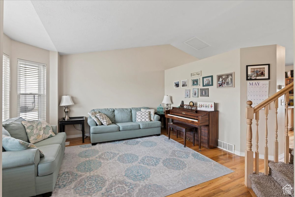 Living area with wood finished floors, stairs, lofted ceiling, and baseboards