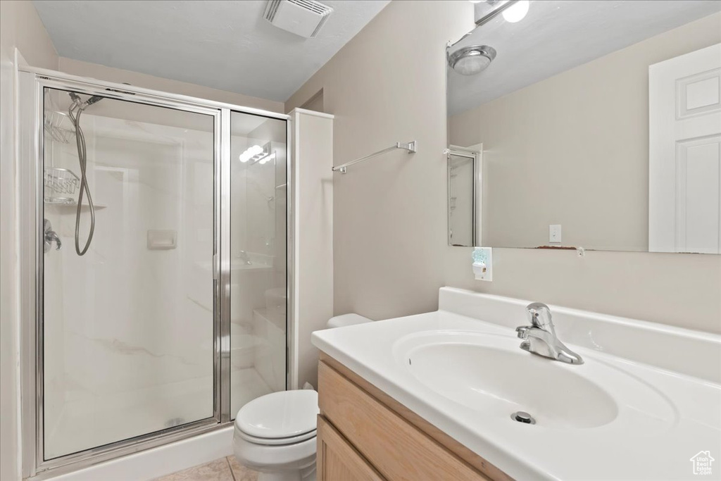 Bathroom featuring toilet, a stall shower, vanity, and tile patterned floors