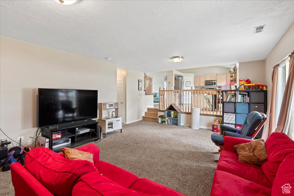 Carpeted living area featuring stairs, a textured ceiling, and baseboards
