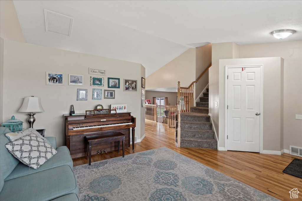 Living area featuring wood finished floors, stairway, baseboards, and vaulted ceiling