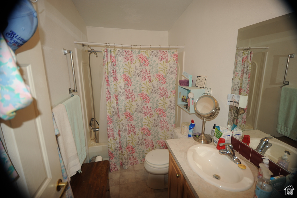 Full bath with shower / bath combination with curtain, vanity, toilet, and tile patterned floors