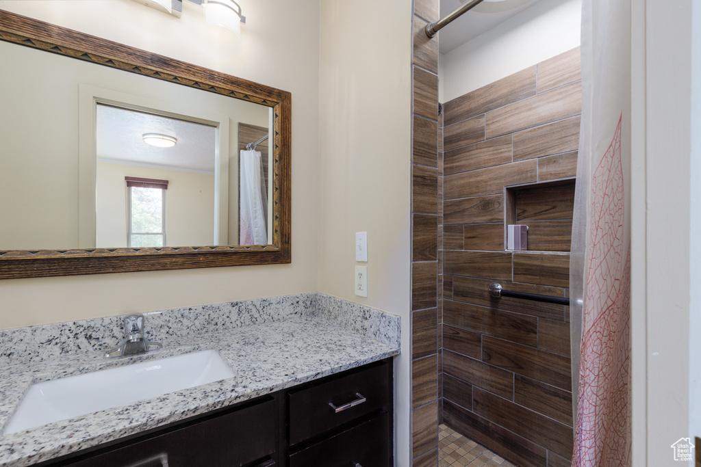 Full bath with a tile shower and vanity